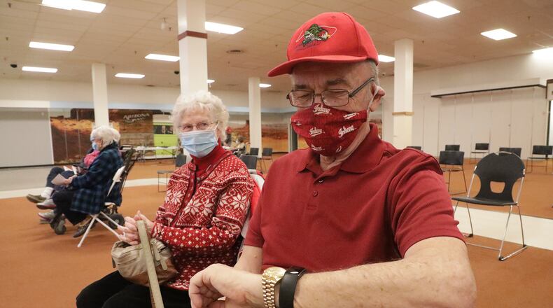 Dr. Ralph Cooper, a retired pediatrician, checks his watch as he waits 15 minutes after getting the COVID vaccine to make sure he doesn't have a reaction. BILL LACKEY/STAFF