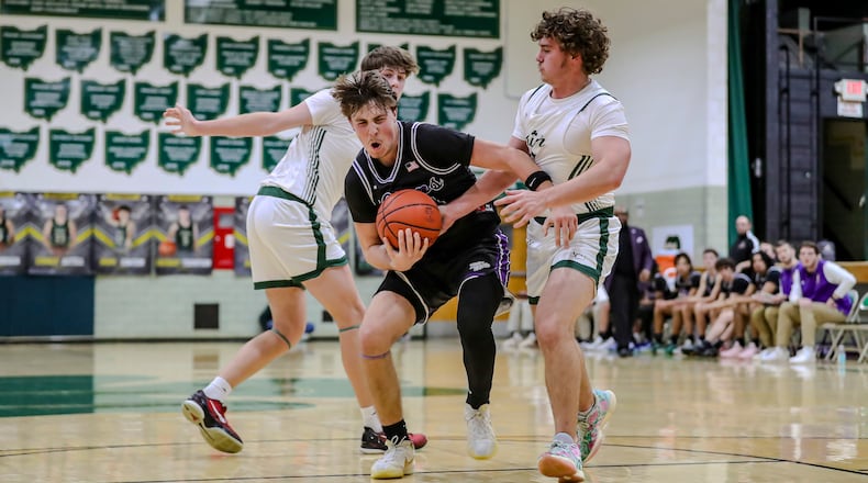 Emmanuel Christian Academy junior Nathan Hudson drives past Catholic Central seniors Charlie Axtell (right) and Zac Thompson during during their game on Tuesday night at Jason Collier Gymnasium in Springfield. The Lions won 73-71 in overtime. MICHAEL COOPER/CONTRIBUTED