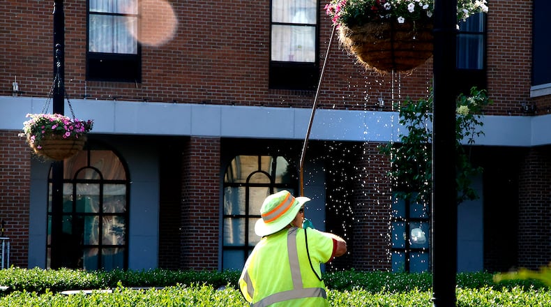 Water drips from a hanging basket as Dick Meeks, a City of Springfield employee, waters the flowers inside Monday morning on the Springfield Esplanade. The city once again placed hanging baskets of flowers on the light poles in the downtown area. In past years, the baskets of overflowing flowers become quite the spectacle thanks to Meeks' hard work. BILL LACKEY/STAFF.