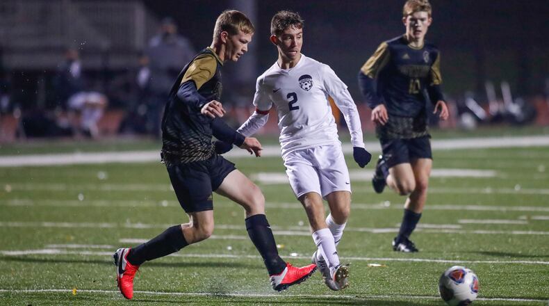 Cutline: Greenon High School senior Jeremiah Mauch (center) passes the ball to a teammate during a Division III district final match against Botkins on Thurdsay night at Bellefontaine High School. The Trojans won 2-1. CONTRIBUTED PHOTO BY MICHAEL COOPER
