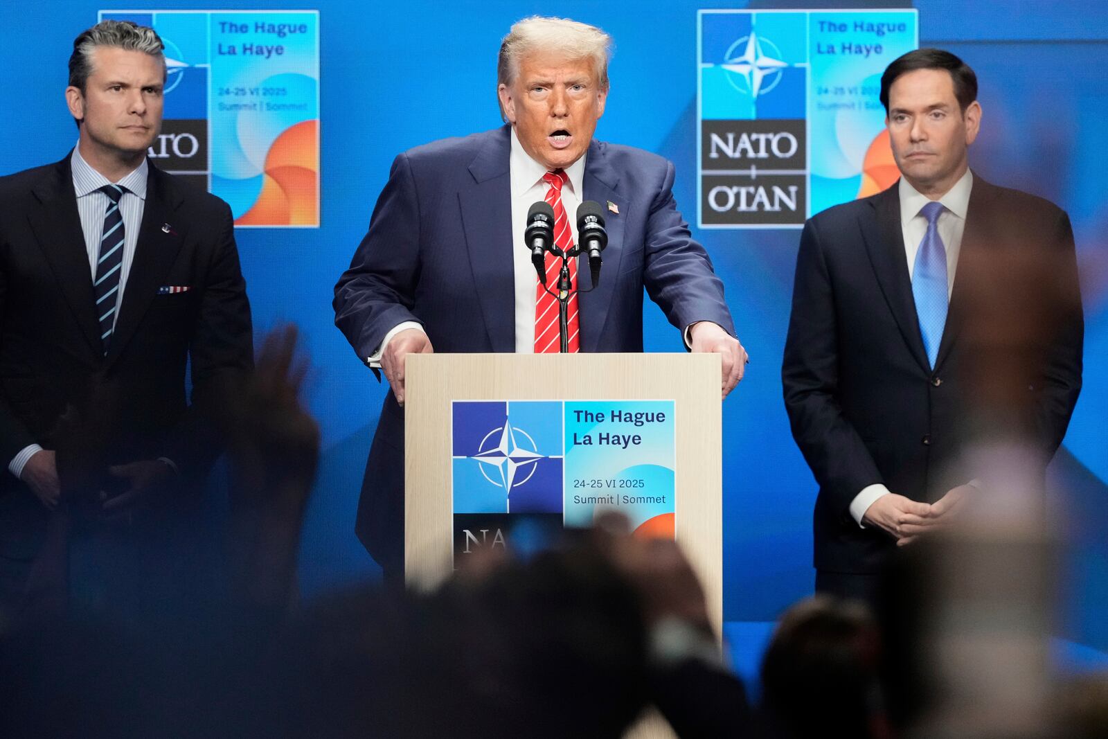 President Donald Trump speaks standing between Secretary of State Marco Rubio, right, and Defense Secretary Pete Hegseth during a press conference after the plenary session at the NATO summit in The Hague, Netherlands, Wednesday, June 25, 2025. (AP Photo/Markus Schreiber)