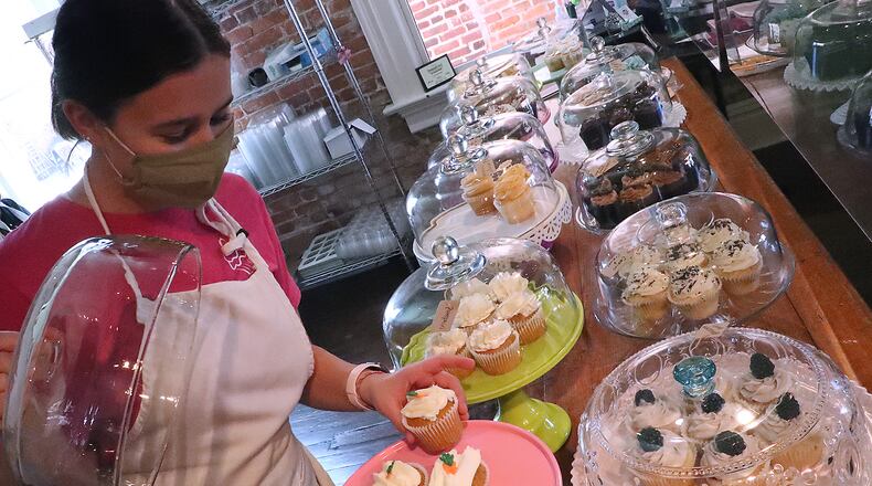 Kerrigan Cushman, an employee of Let's Eat Cake, sets out cupcakes in the show Friday. Let's Eat Cake is one of the downtown Urbana businesses participating in the 3rd Annual Pumpkin Walk. BILL LACKEY/STAFF