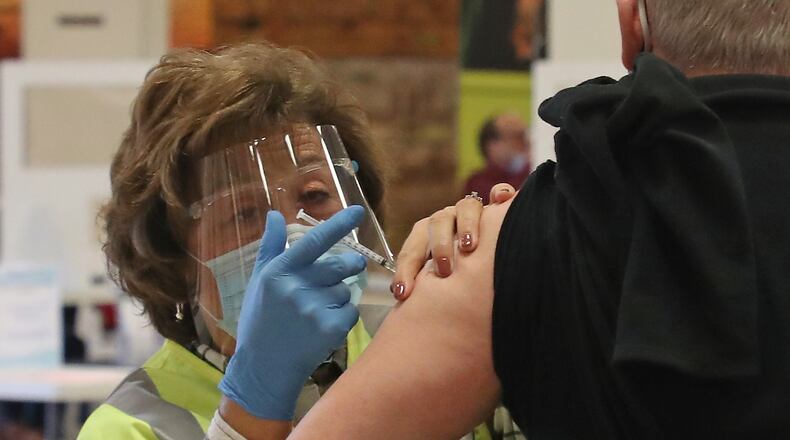 Patricia Hart, a voluteer at the Clark County Combined Health District's COVID vaccine distribution center, gives a Clark County resident his COVID vaccine shots at the Upper Valley Mall Tuesday, Feb. 23, 2021. BILL LACKEY/STAFF