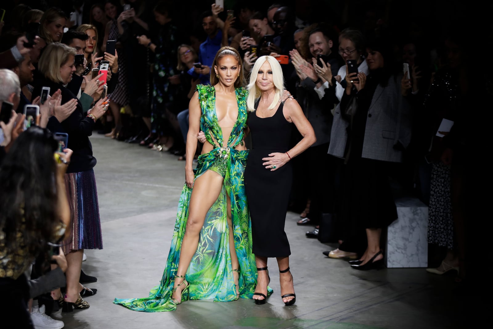 FILE - Actress Jennifer Lopez, left, and designer Donatella Versace accept applause at the conclusion of the Versace Spring-Summer 2020 collection, unveiled during the fashion week, in Milan, Italy, Friday, Sept. 20, 2019. (AP Photo/Luca Bruno, File)