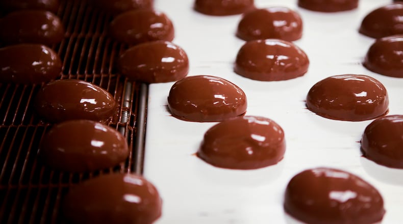 Chocolate covered marshmallows travel down an enrobing belt before they are dunked under a curtain of chocolate for a second time at See’s Candies in Los Angeles. (Bethany Mollenkof/Los Angeles Times/TNS)