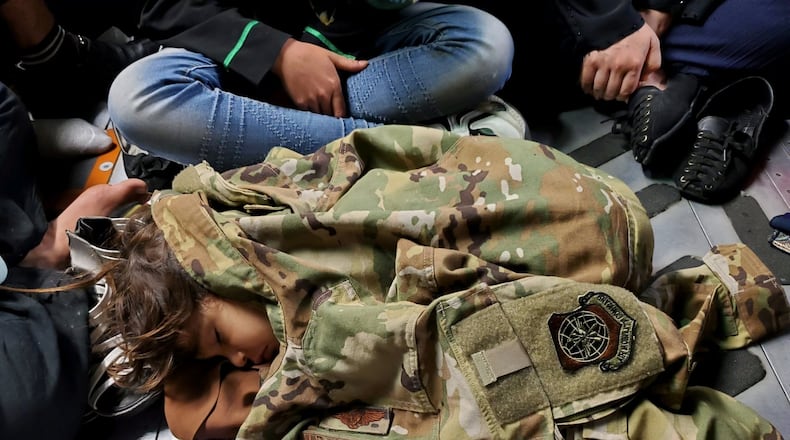 An Afghan child sleeps on the cargo floor of a U.S. Air Force C-17 Globemaster III, kept warm by the uniform of the C-17 loadmaster, during an evacuation flight from Kabul, Afghanistan, Aug. 15, 2021. Operating a fleet of Air National Guard, Air Force Reserve and Active Duty C-17s, Air Mobility Command, in support of the Department of Defense, moved forces into theater to facilitate the safe departure and relocation of U.S. citizens, Special Immigration Visa recipients, and vulnerable Afghan populations from Afghanistan. (U.S. Air Force Courtesy Photo)