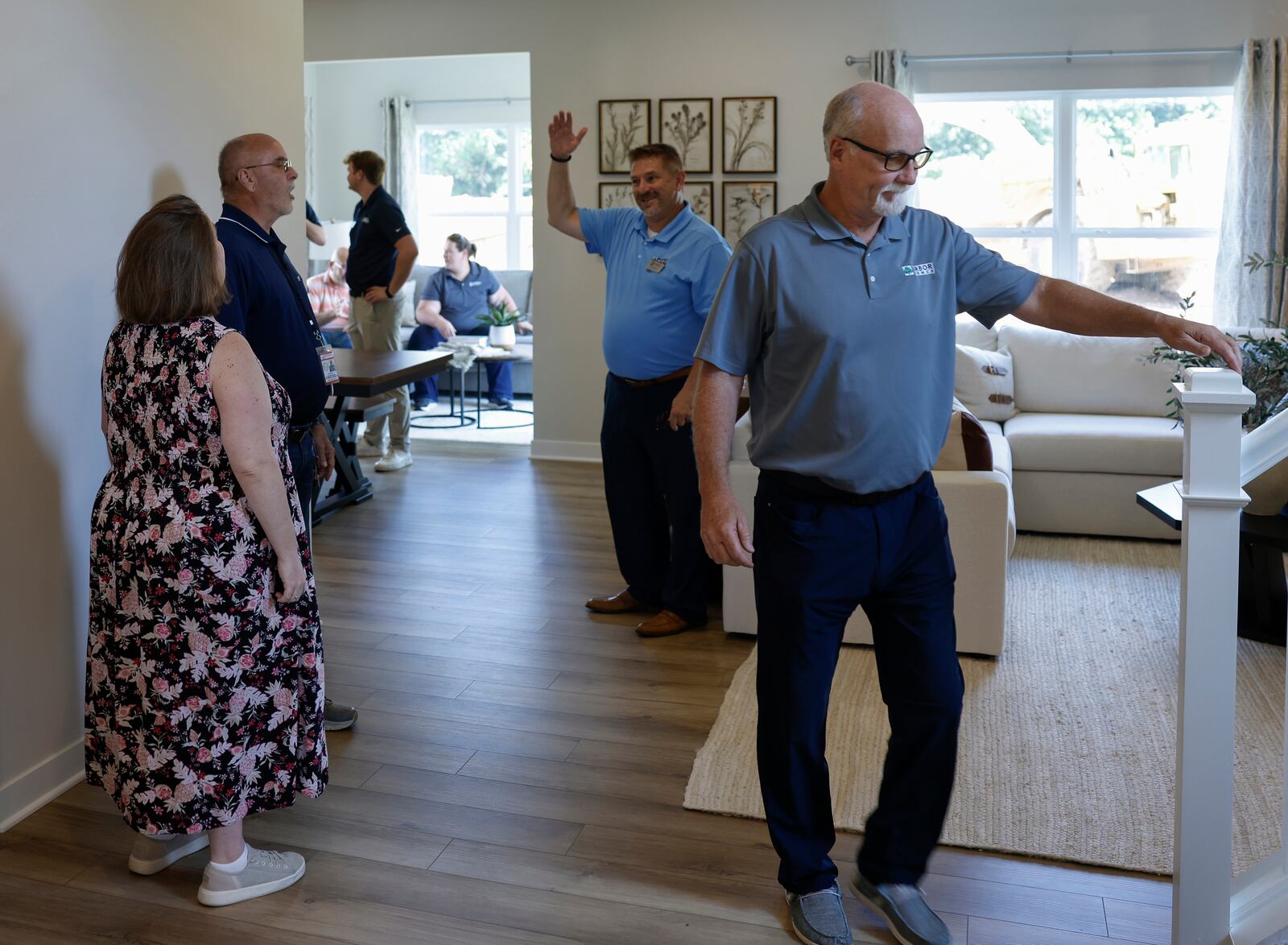 Kevin Baechle, center, regional sales manager of Arbor Homes, socializes as Andy Glassmeyer, right, land acquisition manager of Arbor Homes, prepares to see the upstairs area of a home during the grand opening of Monroe Meadows housing development on Friday, June 27, 2025, in New Carlisle. JOSEPH COOKE/STAFF
