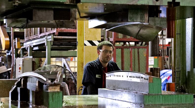 Josh Studebaker, an employee of Pentaflex, operates a press on the manufacturing floor Friday. BILL LACKEY/STAFF