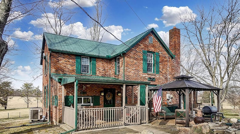 The all-brick farmhouse has 3 bedrooms and about 1,920 sq. ft. of living space. The home is on 5 acres and includes a 4-car, detached garage. The front of the home features mature trees, a covered front porch and gazebo covering a stone patio. CONTRIBUTED PHOTO