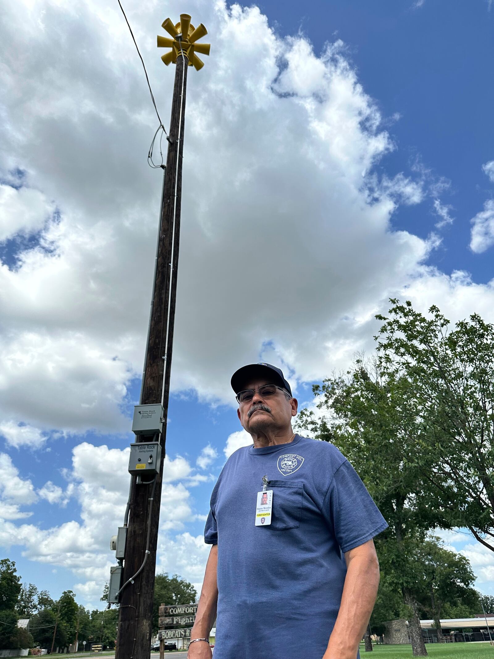 Comfort, Texas, Assistant Fire Chief, Danny Morales stands under a flash flood siren in the community's park on Thursday, July 10, 2025. (AP Photo/Sean Murphy)
