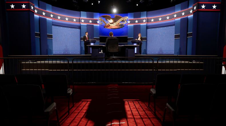 The moderator casts a long shadow as students stand in for the candidates during a rehearsal Tuesday, Oct. 18, 2016 for the third presidential debate between Republican presidential nominee Donald Trump and Democratic presidential nominee Hillary Clinton at UNLV in Las Vegas. (AP Photo/John Locher)