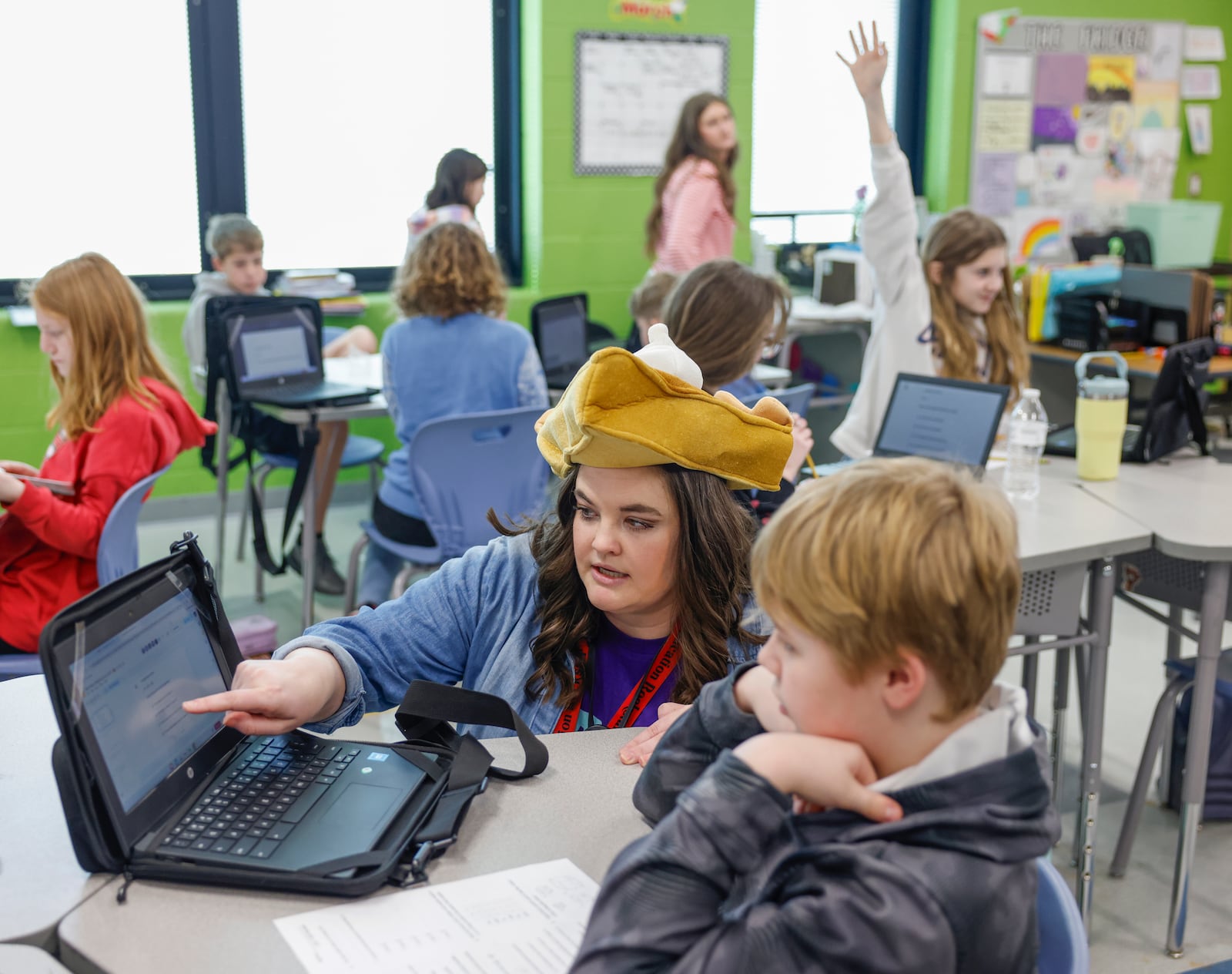 Fifth grade math teacher Allison Cody helps her student work through an equation at Greenon Elementary School on Friday, March 13, 2026, in Enon. She's wearing a pie on her head in celebration of Pi Day, which is March 14. She's one of four teachers who will receive an Excellence in Teaching Award on March 23. JOSEPH COOKE/STAFF