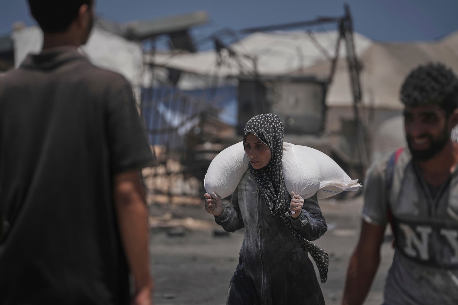 Palestinians carry sacks of flour unloaded from a humanitarian aid convoy that reached Gaza City from the northern Gaza Strip, Tuesday, July 22, 2025. (AP Photo/Jehad Alshrafi)