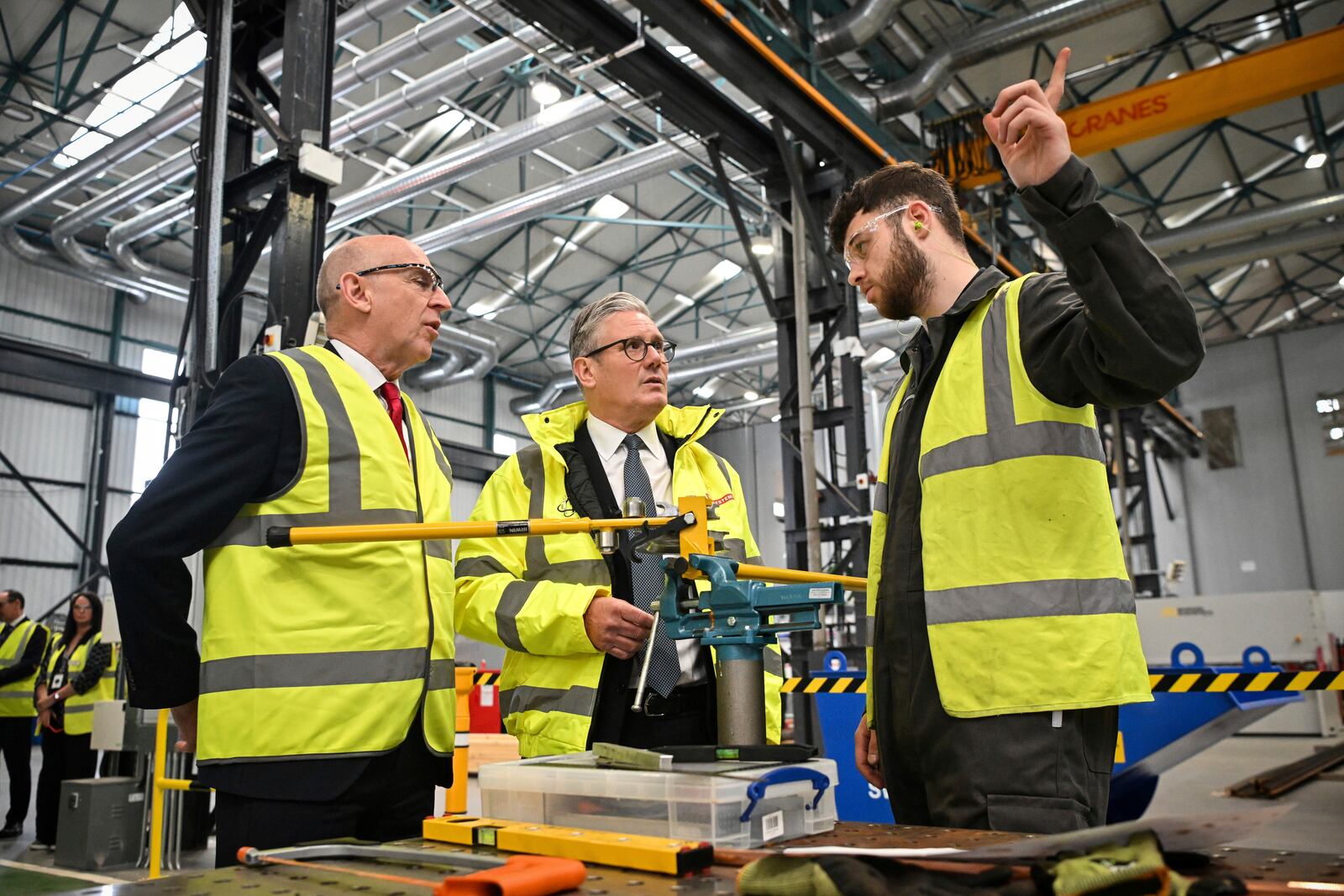 Britain's Prime Minister Keir Starmer, center, and Britain's Defence Secretary John Healey, left, speak to a member of staff during a visit to the BAE Systems'Govan facility, in Glasgow, Scotland, Monday June 2, 2025. (Andy Buchanan, Pool Photo via AP)