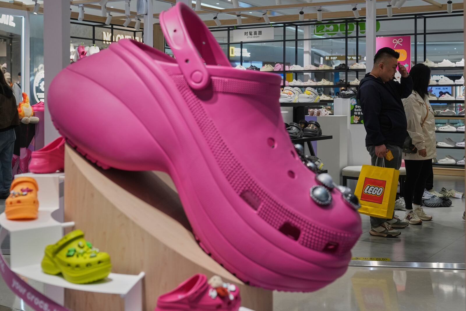 A Chinese couple shop at a Crocs store inside a shopping mall, in Beijing, Saturday, April 12, 2025. (AP Photo/Andy Wong)