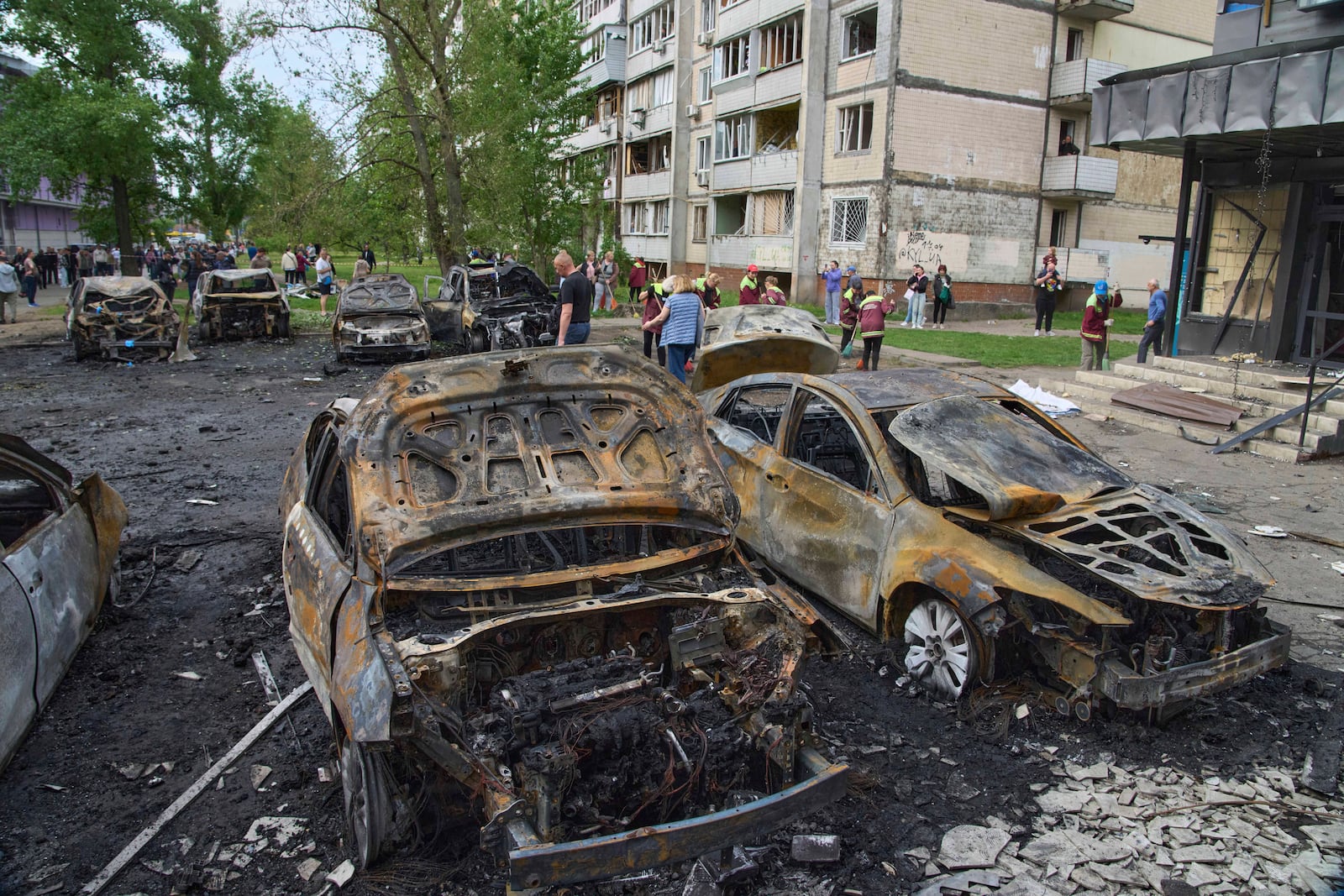 Municipal workers clean up burnt cars in the residential area following Russia's drone attack in Kyiv, Ukraine, Sunday, May 4, 2025. (AP Photo/Efrem Lukatsky)