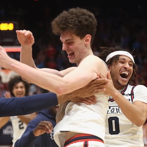 Dayton's Javon Bennett, right, and Zed Key, left, celebrate with Amaël L'Etang after his game-winning basket in overtime against Loyola Chicago on Saturday, Jan. 18, 2025, at UD Arena. David Jablonski/Staf