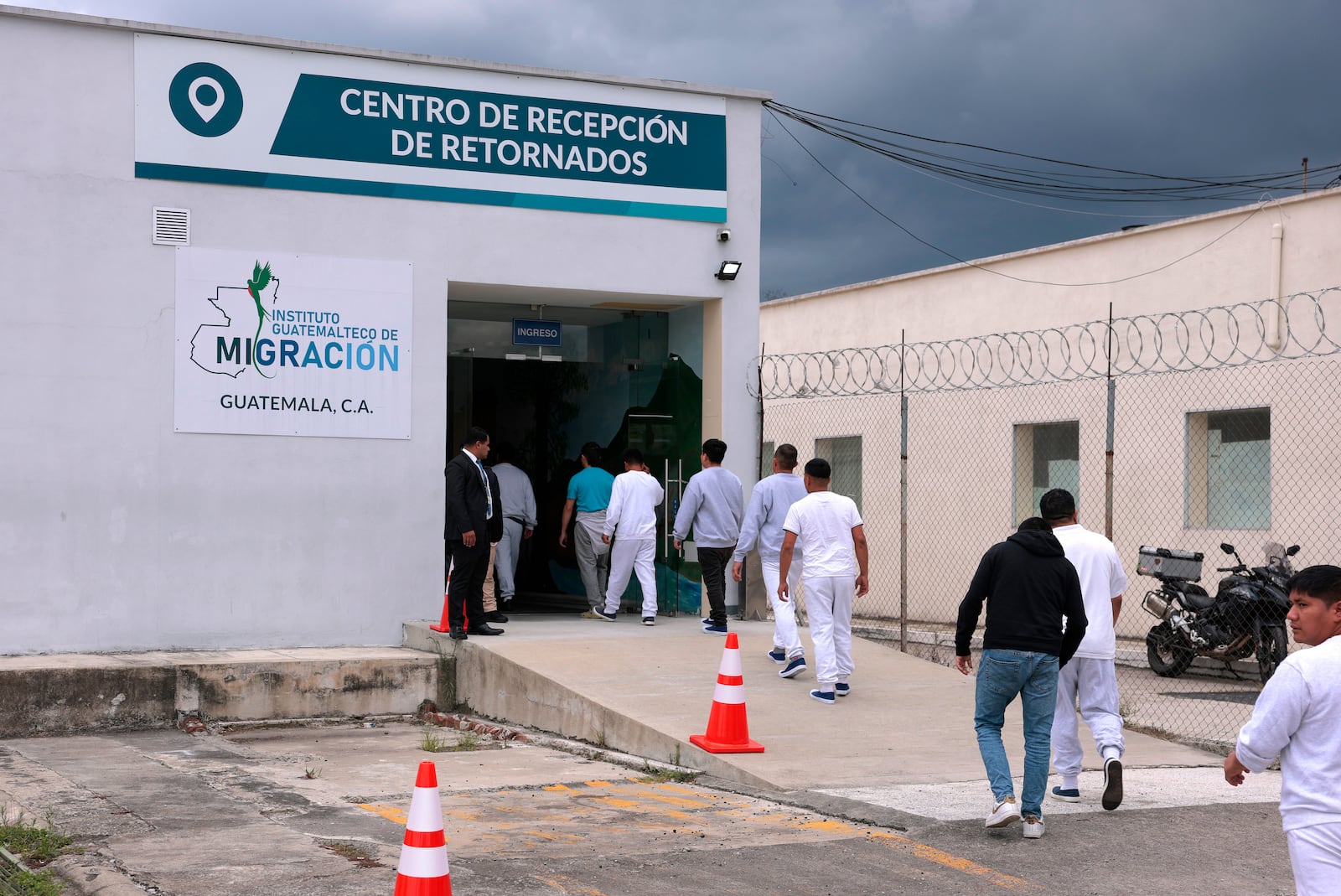 People deported from the United States walk into a processing center after arriving on a repatriation flight, during a Department of Homeland Security operations tour for visiting Homeland Security Secretary Kristi Noem, at La Aurora International Airport in Guatemala City, Thursday, June 26, 2025. (Anna Moneymaker/Pool Photo via AP)
