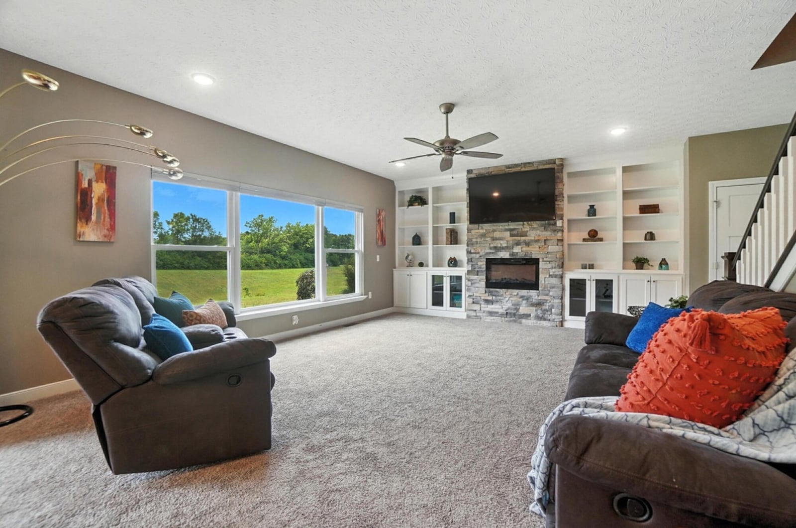 The great room has neutral carpeting and a stacked stone fireplace with built in entertainment units on either side. CONTRIBUTED