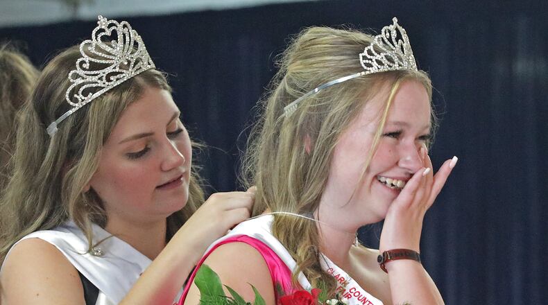 Kendall Spencer, the 2021 Clark County Fair Queen, wipes away tears as 2020 Fair Queen Mozie Van Raaij puts a diamond necklace on her Saturday at the conclusion of the contest. BILL LACKEY/STAFF