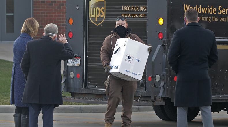 Gov. Mike DeWine and his wife, Fran, along with Springfield Regional Medical Center President Adam Groshans, right, greet a UPS driver as he delivers the first COVID-19 vaccine at the hospital Tuesday morning. BILL LACKEY/STAFF