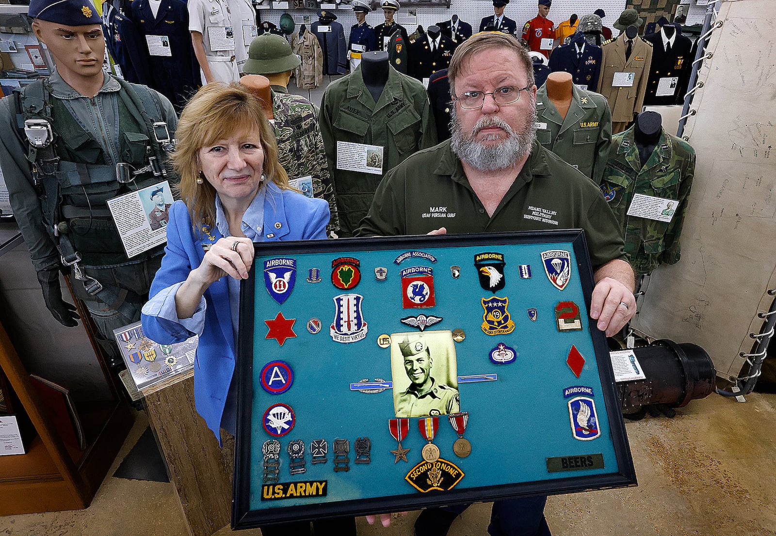 Catherine Beers-Conrad with her husband Mark Conrad proudly hold up one of the displays featuring her father from the Vietnam war at the Miami Valley Military History Museum. MARSHALL GORBY\STAFF
