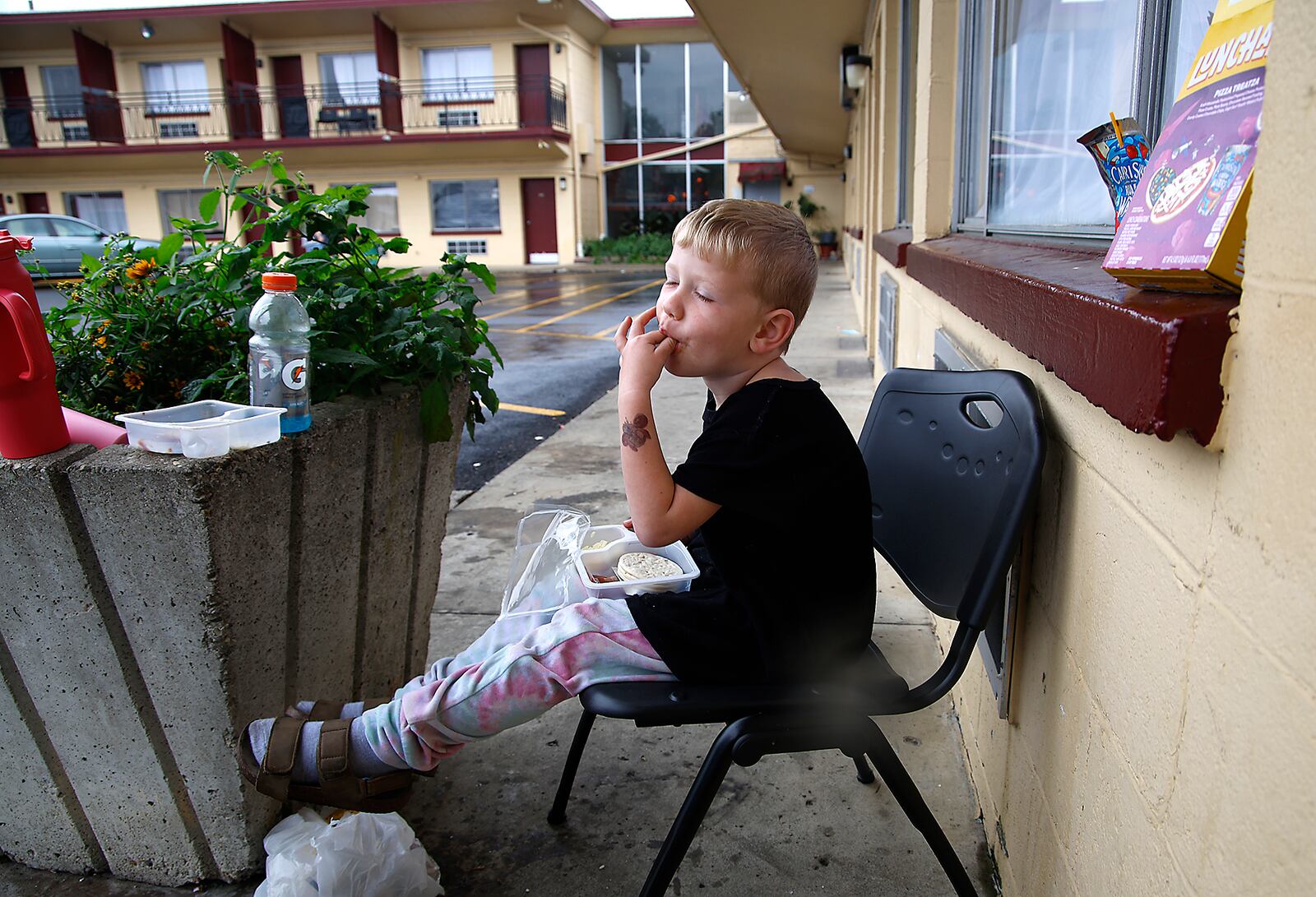 Colton Park, 3, enjoys his Lunchable while sitting outside his family's room at the Executive Inn shelter Wednesday, Sept. 27, 2023. According to Colton's mother, they are not allowed to eat in their rooms so they sit outside. BILL LACKEY/STAFF
