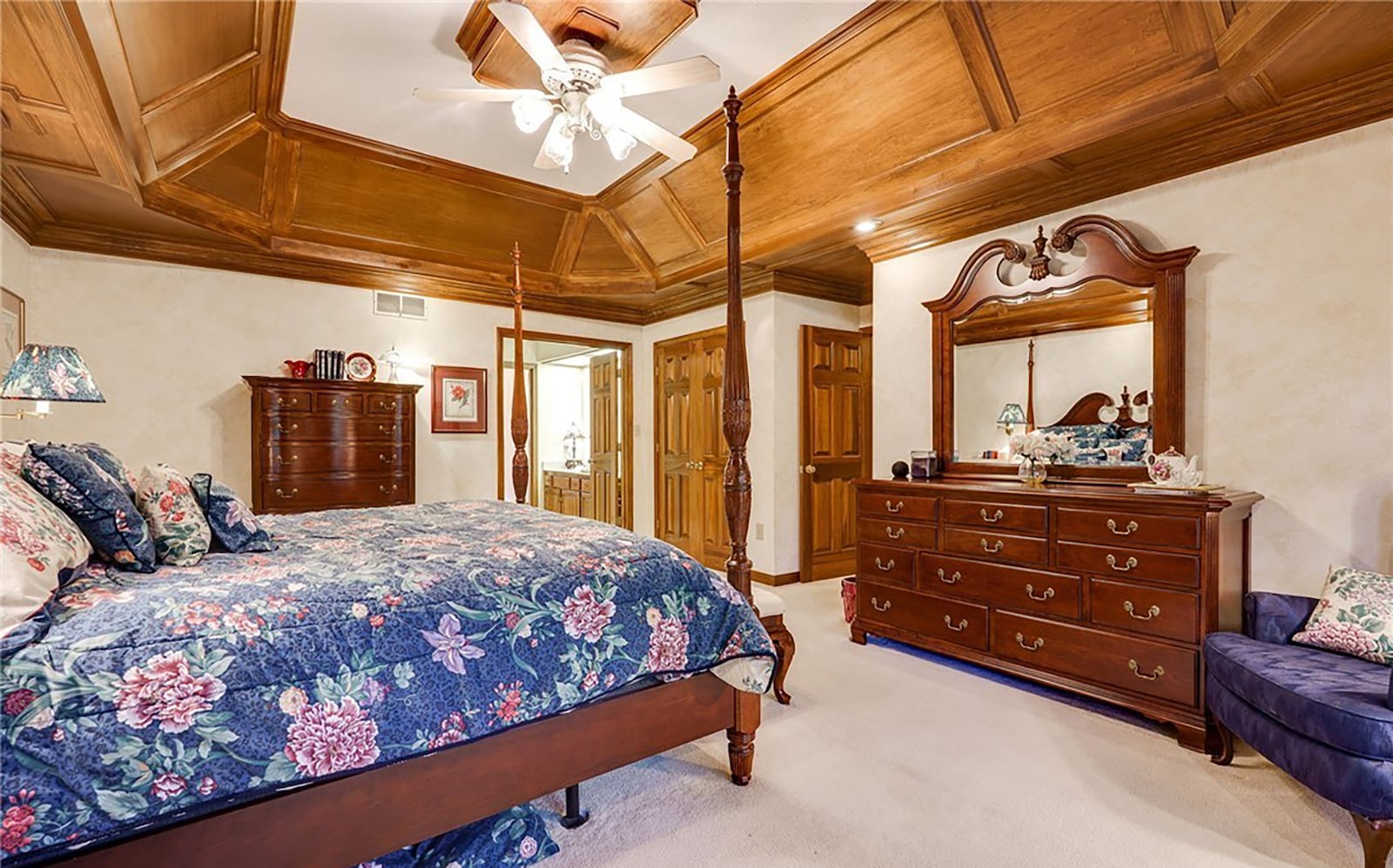 The second floor primary suite is carpeted and has a high end tray ceiling with wood accents and a ceiling fan. CONTRIBUTED