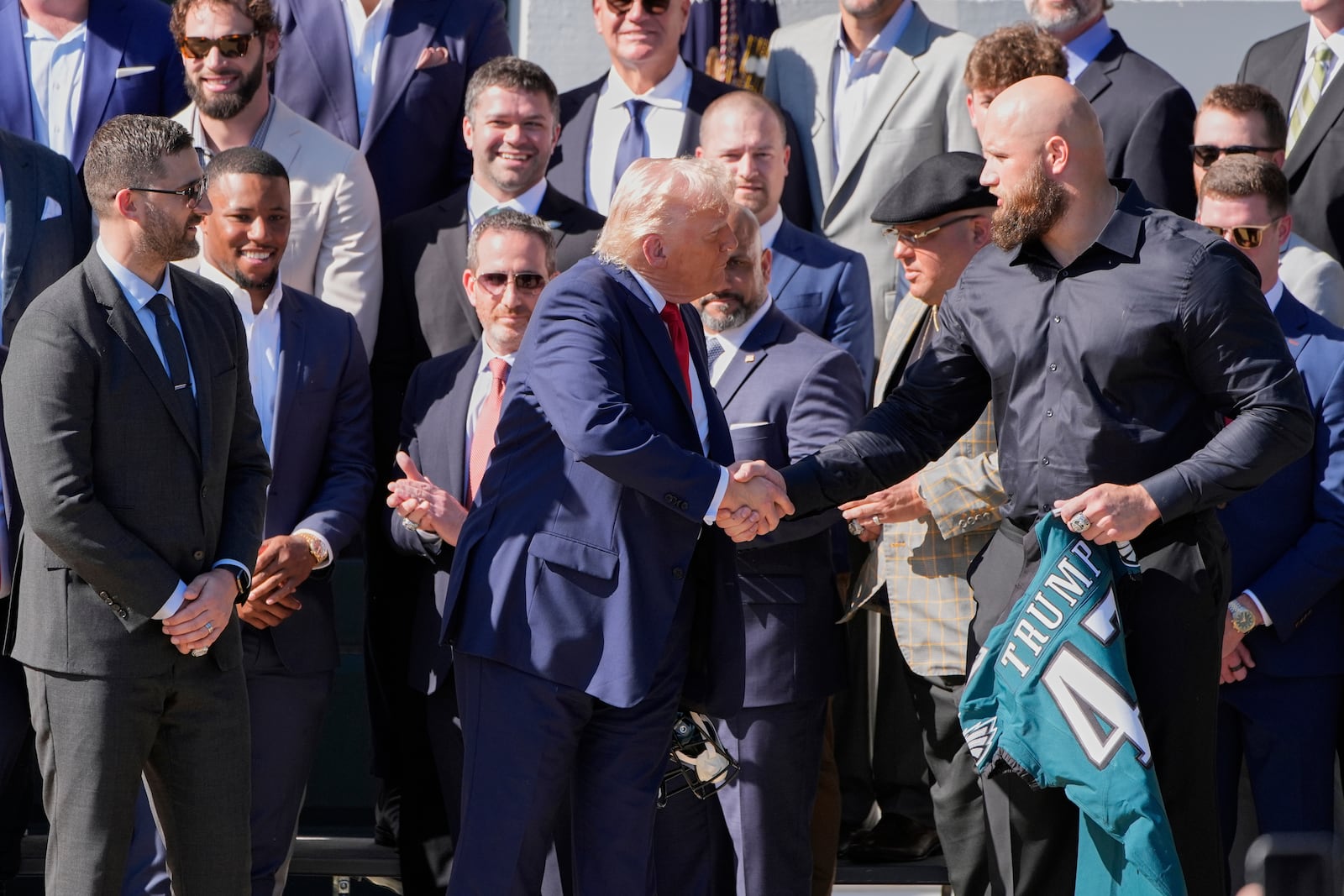 President Donald Trump, left, shakes the hand of Philadelphia Eagles NFL football player Lane Johnson as Johnson presents Trump with a jersey during a ceremony welcoming the Super Bowl champion team to the South Lawn of the White House, Monday, April 28, 2025, in Washington. (AP Photo/Alex Brandon)