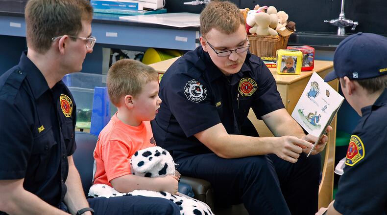 Members of the Springfield Fire & Rescue Division, from left, Austin Paul, Riley Linn and Cole Schlereth read to Silas Parfitt, a preschooler at Clark Early Learning Center, as he hugs his stuffed dalmation Tuesday, March 5, 2024. The Fire & Rescue Division along with the Springfield police were participating in the Read Across America event. BILL LACKEY/STAFF