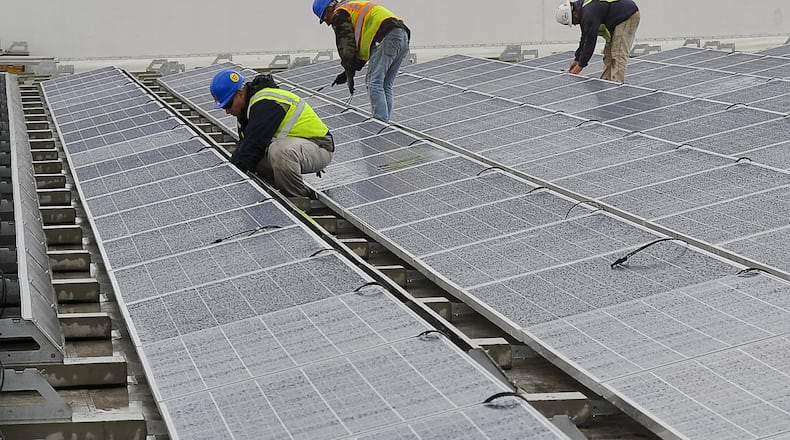 Workers maintain the 6,200 solar panels on the roof of the Assurant Group buildings in Springfield. BILL LACKEY/STAFF