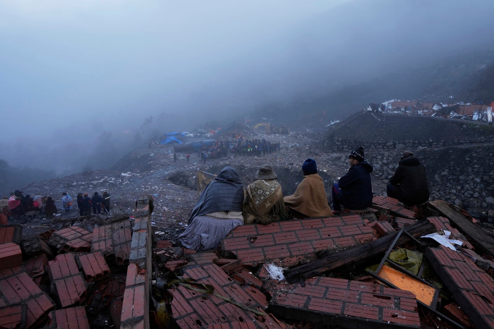 Relatives of miners look out from rubble after an explosive attack near the Hijos de Ingenio gold mine in Yani, Bolivia, Thursday, April 3, 2025. (AP Photo/Juan Karita)