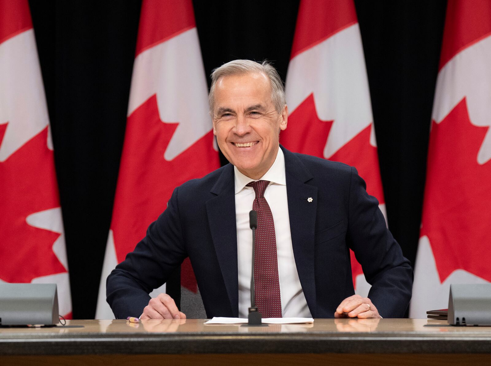 Prime Minister Mark Carney smiles as he takes his seat at his first news conference since winning the federal election, in Ottawa, Friday, May 2, 2025. (Adrian Wyld /The Canadian Press via AP)