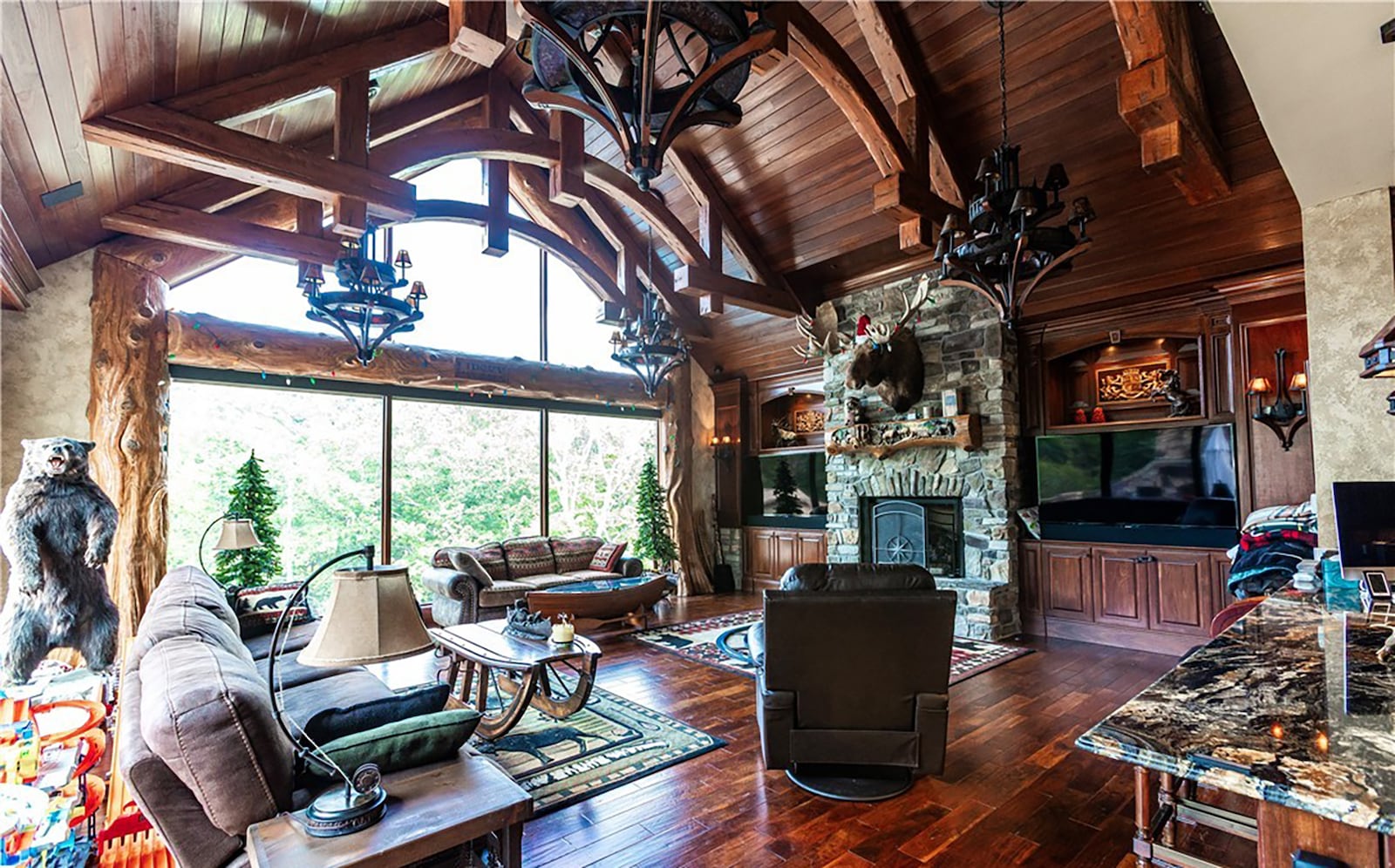 The family room has a wood beamed ceiling, wood floors, a stacked stone fireplace and a picture window with rough hewn log accents. CONTRIBUTED