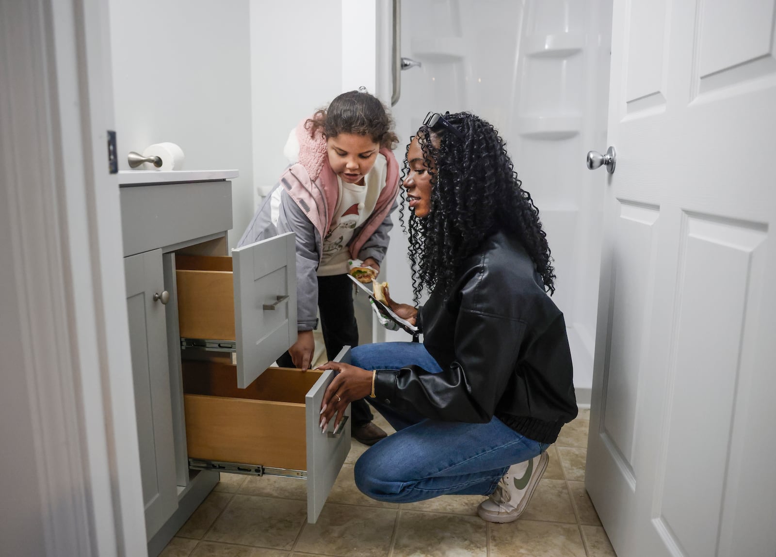 Rileyanna Foster, left, 8, and her cousin Imani Fudge look at drawers in a bathroom following a home dedication hosted by the Habitat for Humanity of Greater Dayton on Friday, Dec. 12, 2025, in Springfield. The ceremony was for Foster and her grandmother Gwendolyn Iheme, who will live in this house. JOSEPH COOKE/STAFF