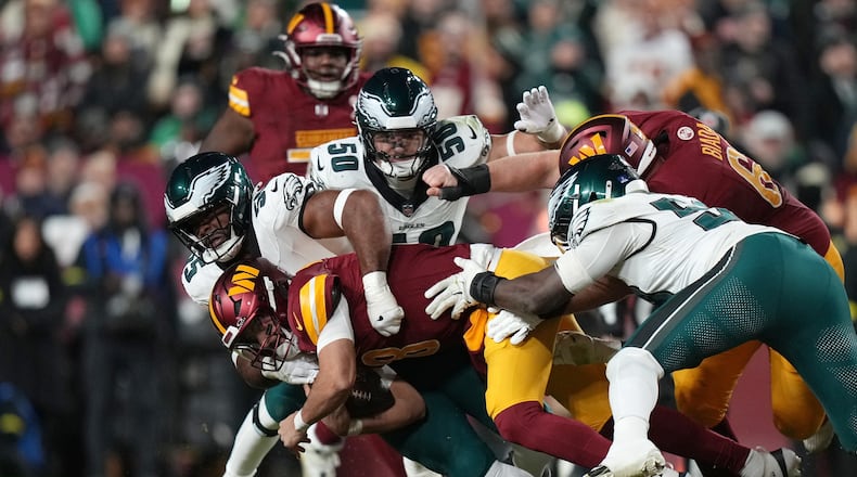 Washington Commanders quarterback Marcus Mariota (8) is sacked by Philadelphia Eagles defensive end Brandon Graham (55) during the first half of an NFL football game, Saturday, Dec. 20, 2025, in Landover, Md. (AP Photo/Stephanie Scarbrough)