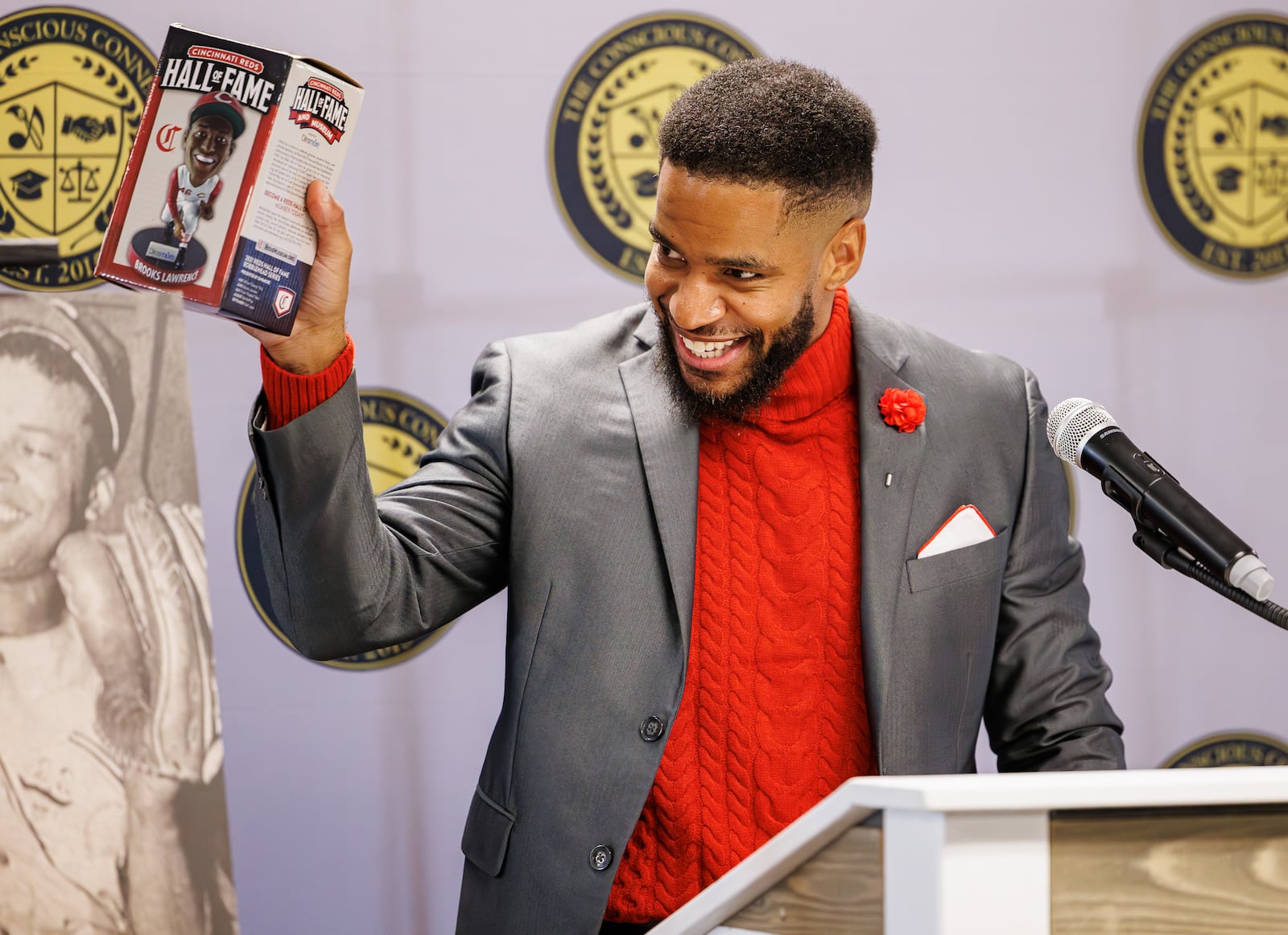 The Conscious Connect CDC co-executive director Karlos Marshall holds up a bobble head of Brooks Lawrence he and other speakers were given by Cheryl D. Lyons during a ceremony unveiling a historical marker for Lawrence on Friday, Nov. 14 at The Dome on South Limestone Street. BRYANT BILLING/STAFF