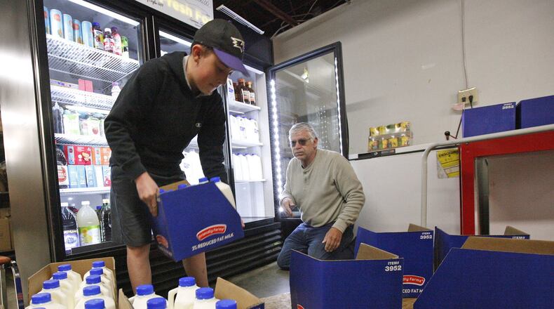 Boy Scout Jakob Spencer, 13, left, restocks a cooler with donated milk at the Xenia Area FISH Food Pantry. The pantry is seeking EDGE grant money from Greene County and other partners to relocate to a larger county-owned building in Xenia that would nearly triple the amount of space for the operation. TY GREENLEES / STAFF