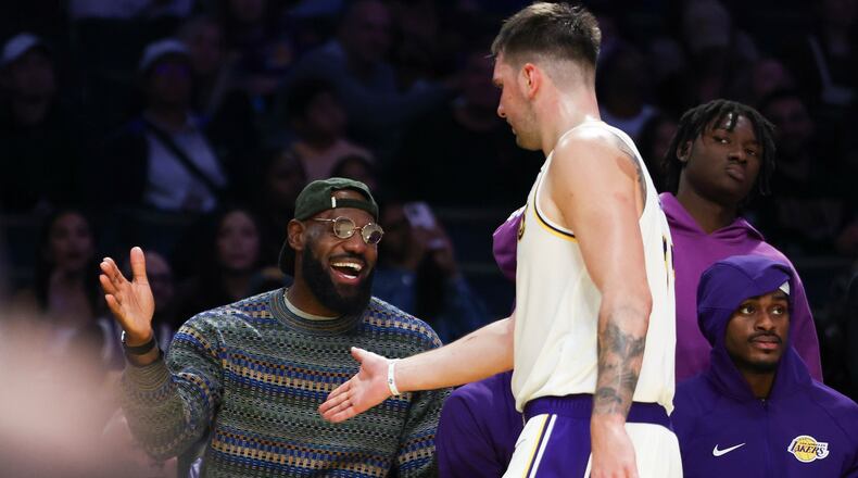 Los Angeles Lakers forward LeBron James, left, and guard Luka Doncic, center, celebrate as forward Jarred Vanderbilt, right, looks on during the second half of an NBA basketball game against the Miami Heat, Sunday, Nov. 2, 2025, in Los Angeles. (AP Photo/Jessie Alcheh)