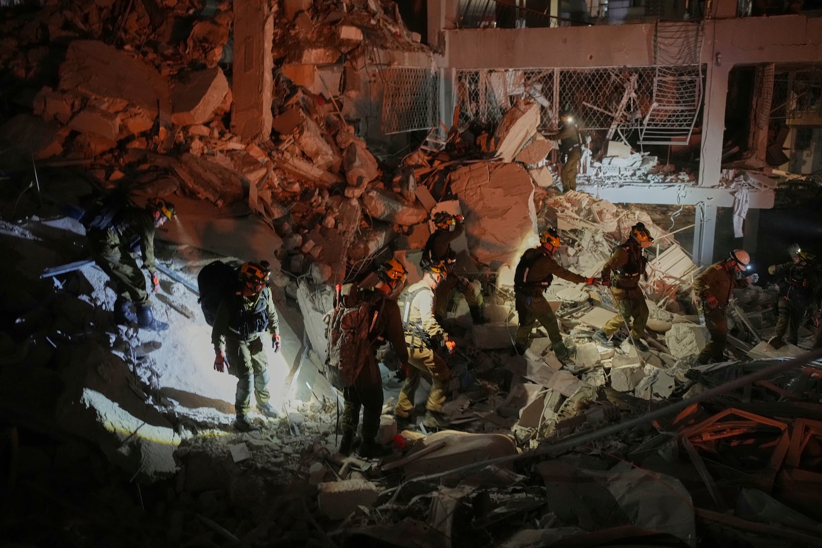 Israeli security forces inspect a destroyed building that were hit by a missile fired from Iran, near Tel Aviv, Israel, early Sunday, June 15, 2025. (AP Photo/Ohad Zwigenberg)