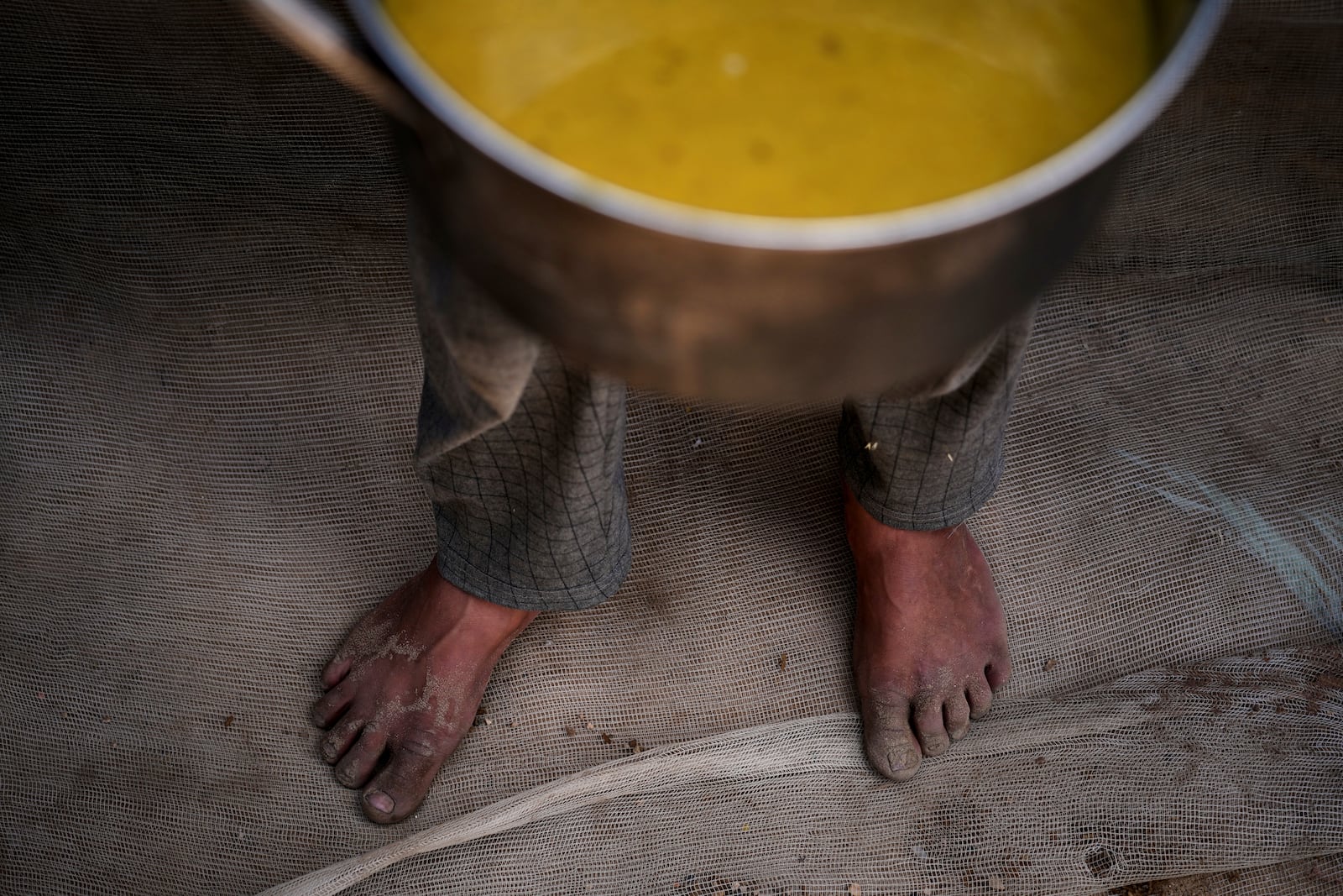 A Palestinian child carries a pot of soup received from a community kitchen in Khan Younis, Gaza Strip, on Saturday, May 3, 2025. (AP Photo/Abdel Kareem Hana)