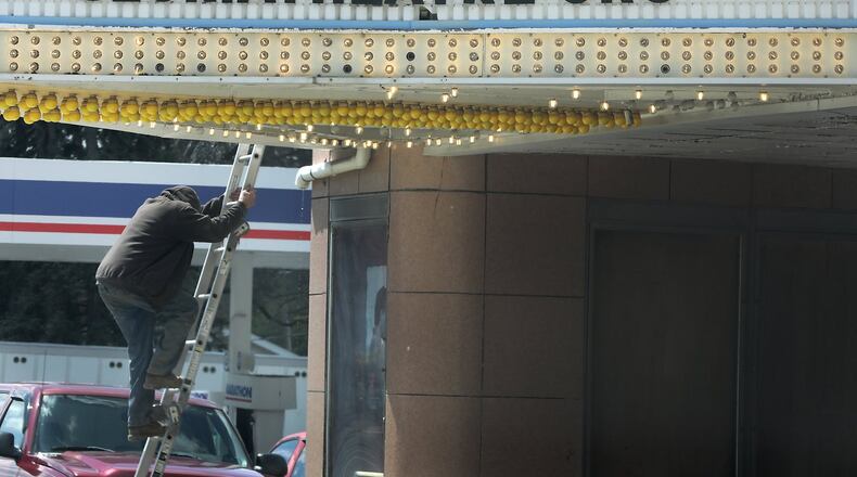 A worker climbs down a ladder from the roof of the Gloria Theatre in Urbana. BILL LACKEY/STAFF