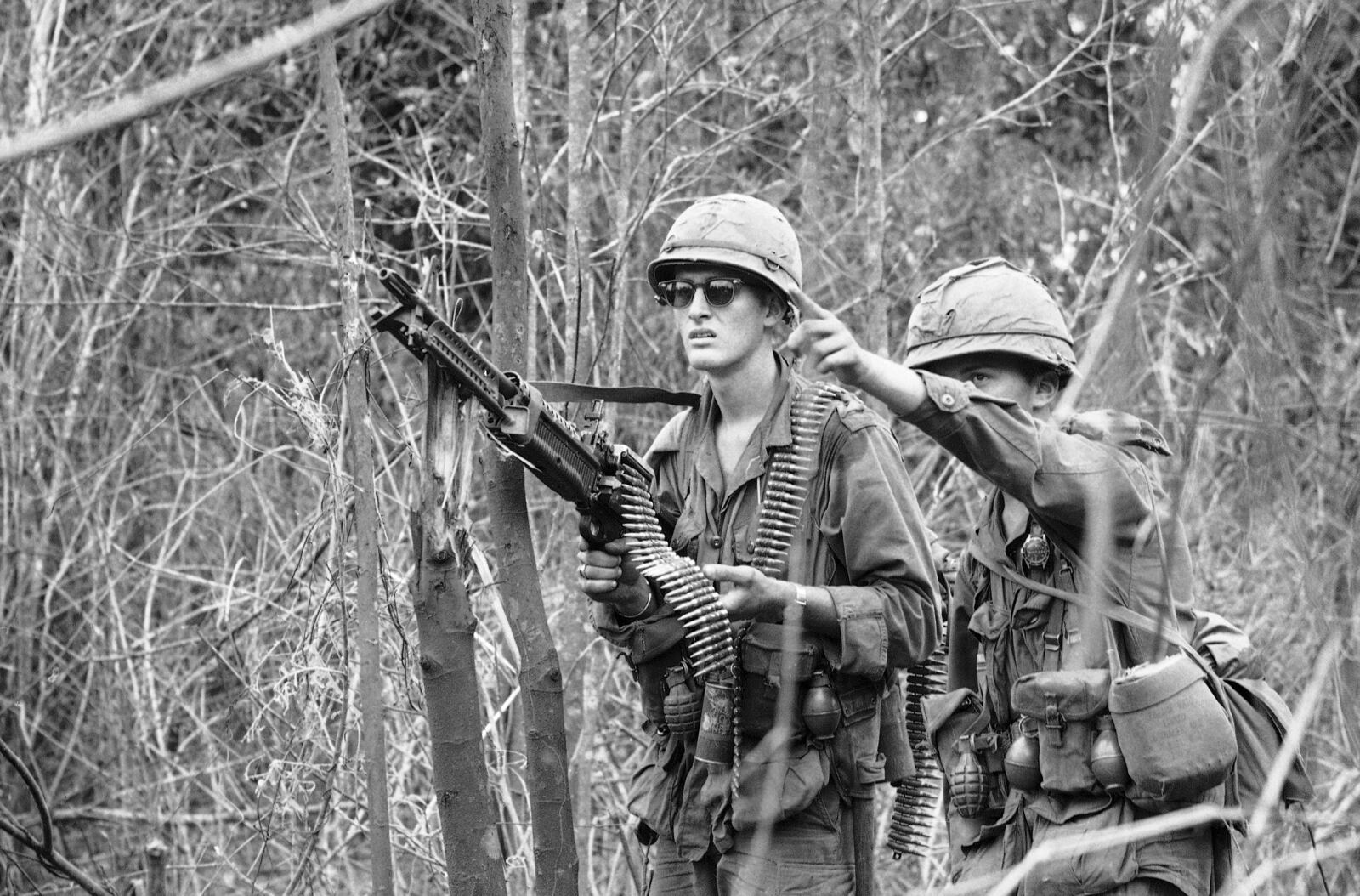 FILE- Infantryman points out a suspicious shadow in a tree to his machine gunner as they move on patrol near the Cambodian Border west of Pleiku in Vietnam on Nov. 26, 1966. Troops of the 25th Infantry Division (1st Battn. 14th Inf.) inches through the thick jungle from their base camp after being held up three days by snipers. AP Photo/Horst Faas, File)