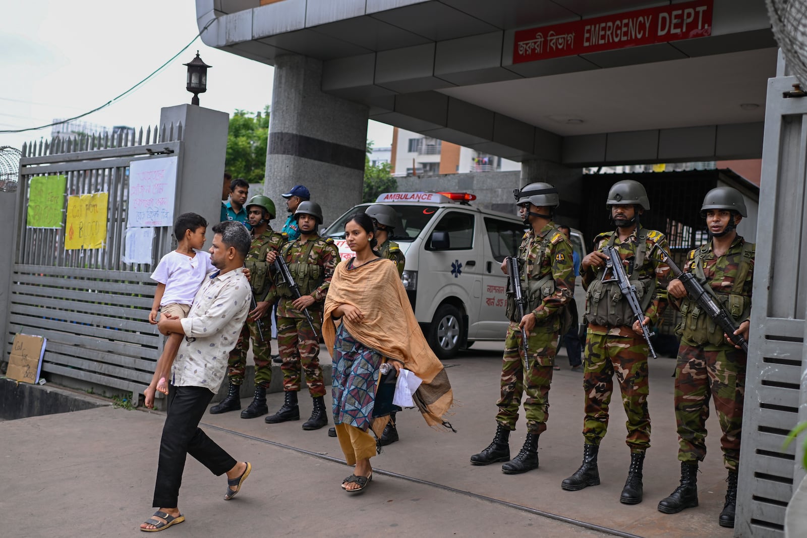 Law enforcement officers stand guard at the entrance of the National Institute of Burn and Plastic Surgery as survivors are treated inside after a Bangladesh air force training aircraft crashed into a school in the nation's capital Monday afternoon in Dhaka, Bangladesh, Tuesday, July 22, 2025.( AP Photo/ Mahmud Hossain Opu)