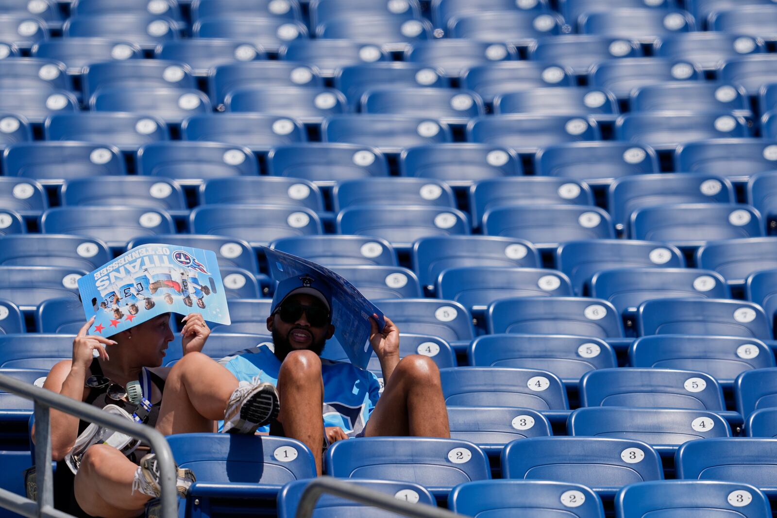 Tennessee Titans fans cover their heads in the heat during "Back Together Weekend" at the team's NFL football training camp Saturday, July 26, 2025, in Nashville, Tenn. (AP Photo/George Walker IV)