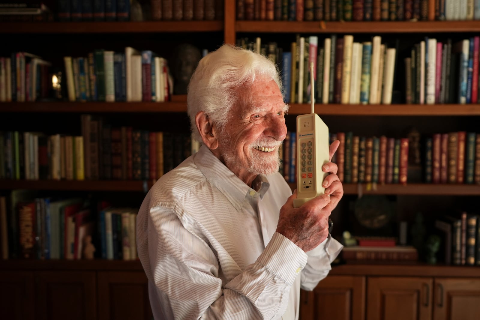Martin Cooper, who led the team that built the first mobile cellphone, sits behind a prototype of that phone at his home, April 4, 2025, in San Diego. (AP Photo/Gregory Bull)