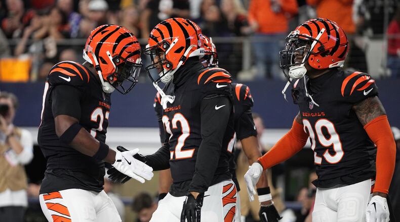 Cincinnati Bengals safety Geno Stone (22), center, celebrates an interception with safety Jordan Battle (27) and cornerback Cam Taylor-Britt (29) during the first half of an NFL football game against the Dallas Cowboys, Monday, Dec. 9, 2024, in Arlington, Texas. (AP Photo/Tony Gutierrez)