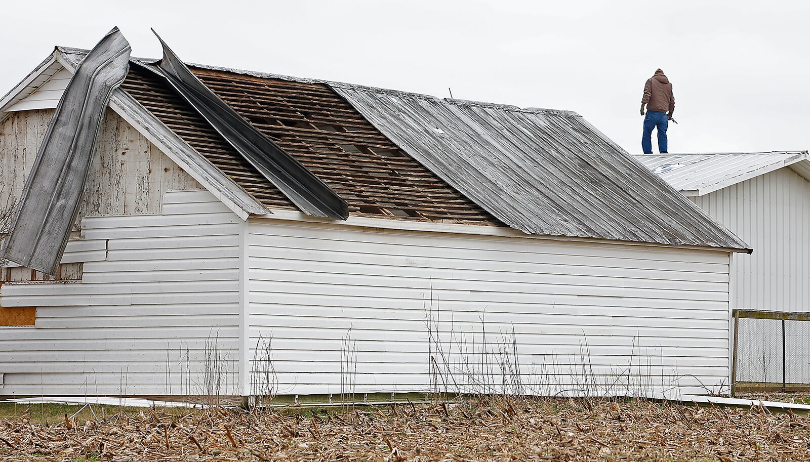 A man surveys the damage to his barn roof Tuesday, Feb. 28, 2023 after a tornado ripped part of it off Monday. BILL LACKEY/STAFF