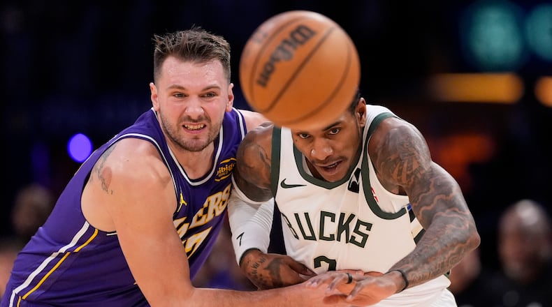 Los Angeles Lakers guard Luka Doncic, left, and Milwaukee Bucks guard Kevin Porter Jr. go after a loose ball during the first half of an NBA basketball game Friday, Jan. 9, 2026, in Los Angeles. (AP Photo/Mark J. Terrill)