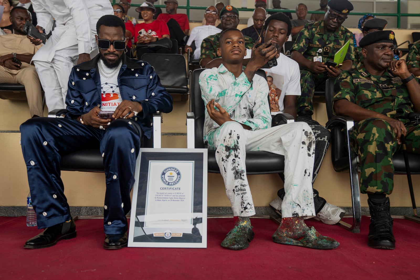 Kanyeyachukwu Tagbo-Okeke, Centre, a 15 year-old autistic artist who won the Guinness World Record for the largest art canvas, attends the World Autism Day in Abuja, Nigeria, Wednesday, April 2, 2025. (AP Photo/David Durowaiye)